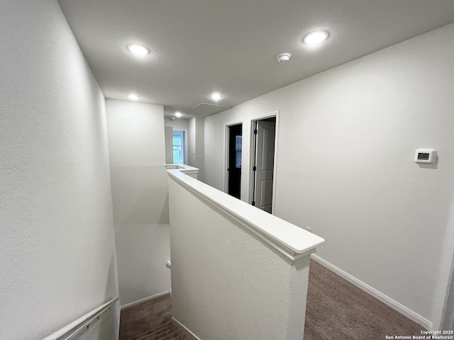 hallway featuring recessed lighting, an upstairs landing, baseboards, and dark carpet