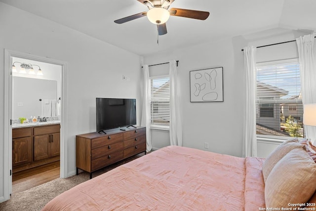 carpeted bedroom with ceiling fan, connected bathroom, and a sink