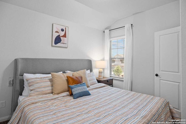 bedroom featuring lofted ceiling and baseboards