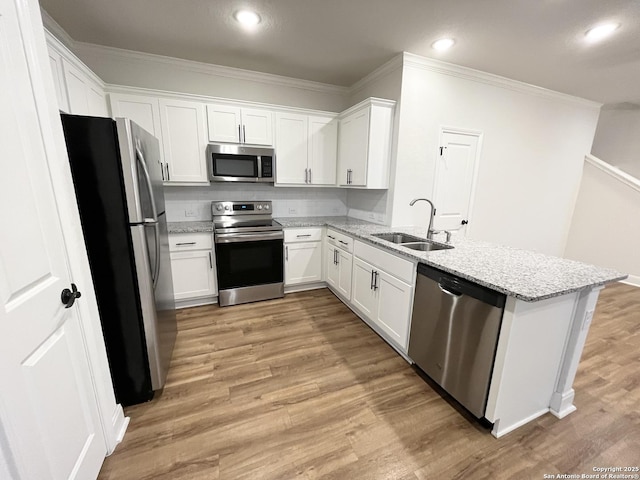 kitchen with a sink, appliances with stainless steel finishes, light wood-style flooring, and ornamental molding