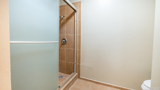 full bath with tile patterned flooring, toilet, and a stall shower