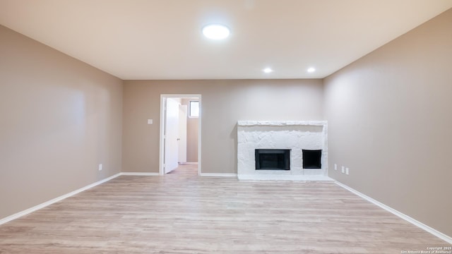 unfurnished living room with light wood finished floors, recessed lighting, a fireplace, and baseboards