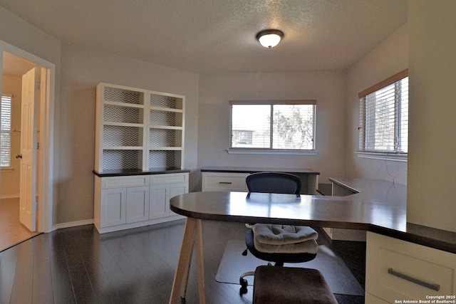 unfurnished office featuring dark wood-type flooring and a textured ceiling