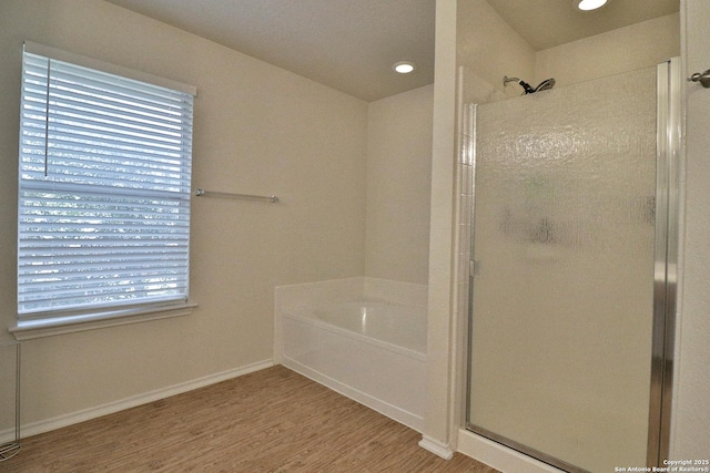 full bathroom with a garden tub, wood finished floors, a stall shower, and baseboards