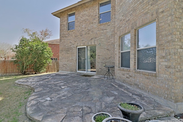 back of house with a patio, brick siding, and fence