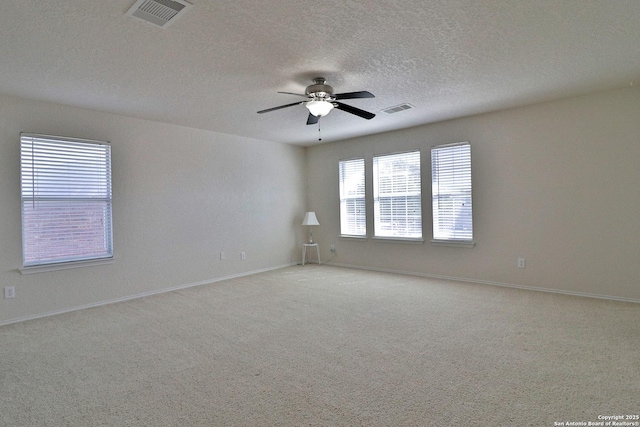 carpeted empty room with baseboards, a ceiling fan, visible vents, and a textured ceiling