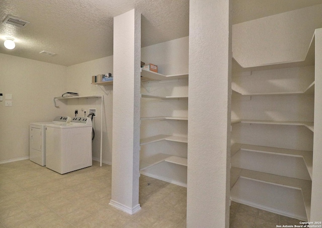 laundry area featuring visible vents, independent washer and dryer, a textured ceiling, light floors, and laundry area