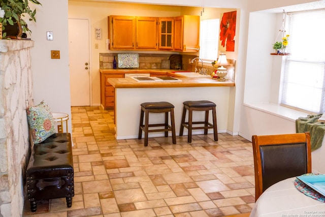 kitchen featuring a peninsula, a breakfast bar area, a wealth of natural light, and a sink