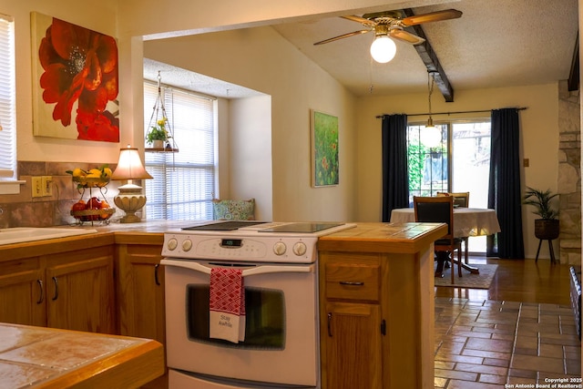 kitchen with white electric range, plenty of natural light, brown cabinets, and tile countertops