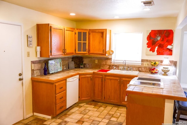 kitchen featuring a kitchen bar, tile counters, visible vents, and a sink