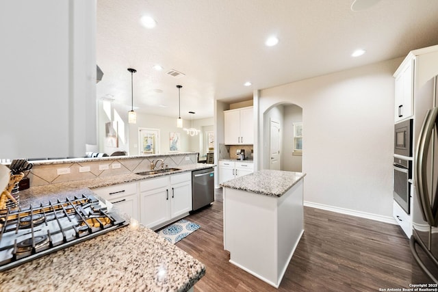 kitchen with visible vents, arched walkways, a sink, stainless steel appliances, and backsplash