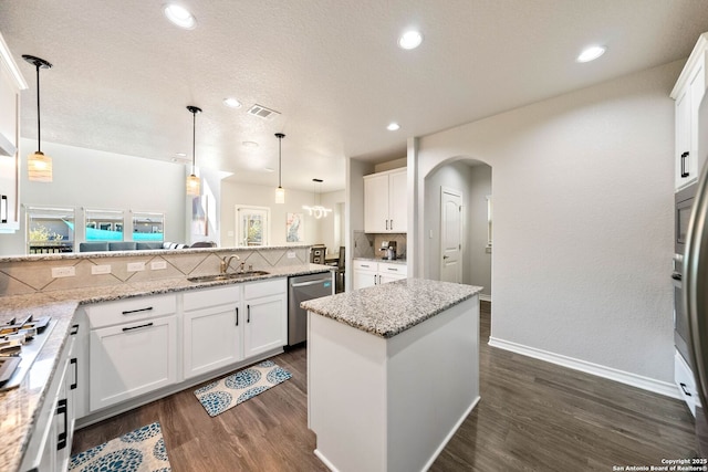 kitchen featuring a sink, backsplash, dark wood-style floors, stainless steel appliances, and arched walkways