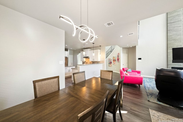 dining space featuring visible vents, stairway, baseboards, and wood finished floors