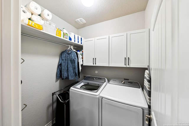 washroom featuring cabinet space, independent washer and dryer, and a textured ceiling