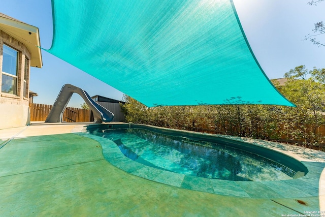 view of swimming pool featuring a patio area, a fenced in pool, a water slide, and a fenced backyard