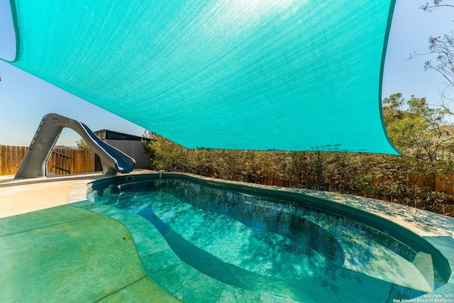 view of pool featuring a fenced backyard, a fenced in pool, and a water slide