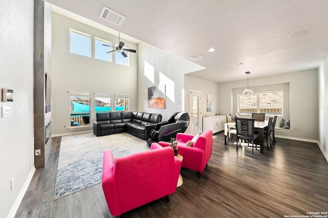 living area featuring visible vents, a textured ceiling, baseboards, and wood finished floors