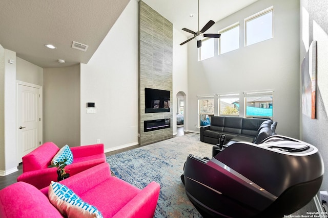 living room with visible vents, baseboards, ceiling fan, and a fireplace