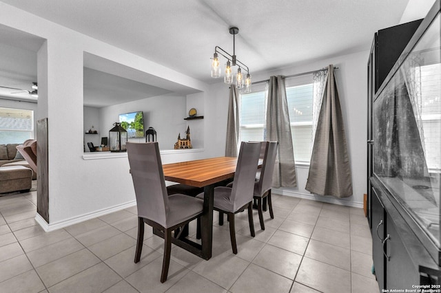 dining room with light tile patterned floors, ceiling fan with notable chandelier, and baseboards