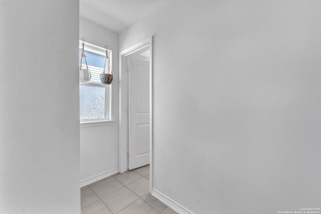 corridor with light tile patterned floors and baseboards