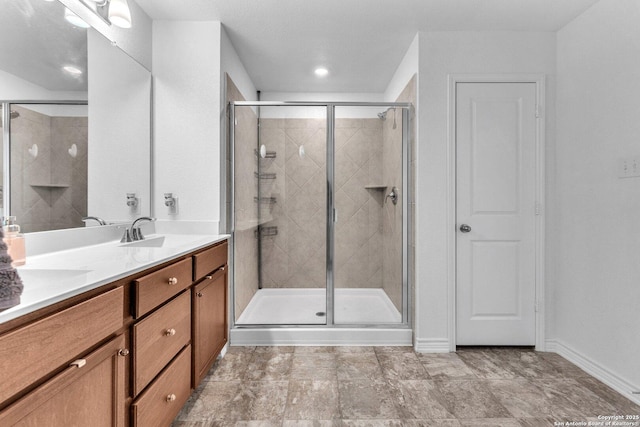 full bath featuring a stall shower, vanity, and baseboards