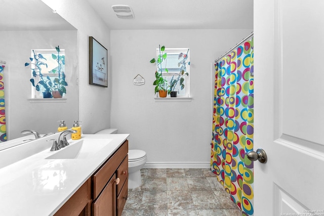 bathroom with visible vents, stone finish flooring, baseboards, toilet, and vanity