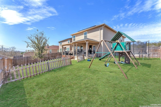 rear view of property with a patio area, a trampoline, a fenced backyard, and a yard