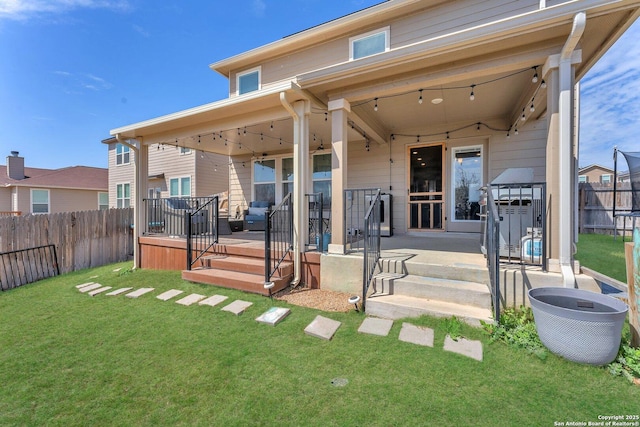 rear view of house with a lawn, a patio, a wooden deck, and a fenced backyard