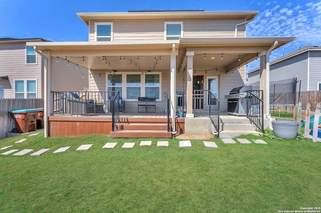 back of property with a yard, a trampoline, and fence