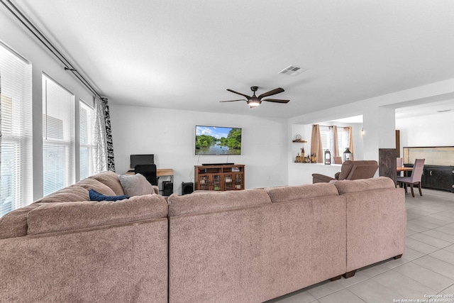 living room with light tile patterned floors, visible vents, and ceiling fan