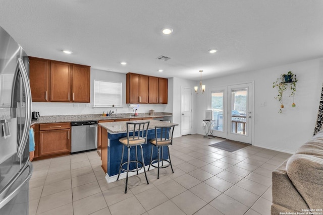 kitchen with brown cabinets, a breakfast bar area, visible vents, and stainless steel appliances