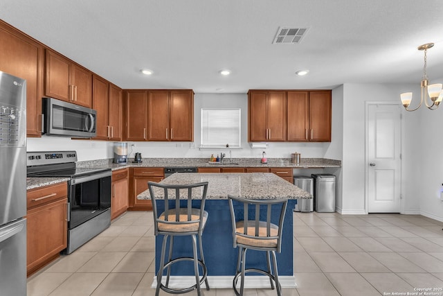 kitchen featuring light stone counters, light tile patterned floors, appliances with stainless steel finishes, and a sink