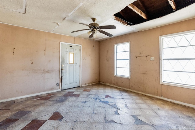 empty room featuring tile patterned floors, baseboards, a textured ceiling, and ceiling fan