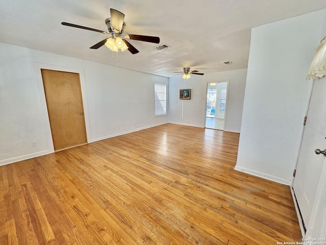 unfurnished room featuring light wood finished floors, visible vents, and baseboards