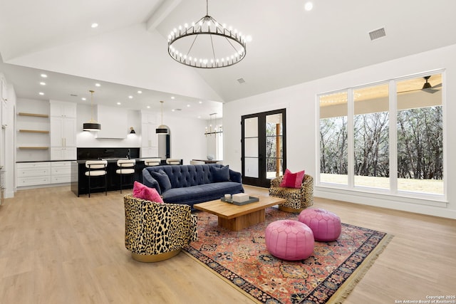 living area with light wood finished floors, visible vents, beamed ceiling, a notable chandelier, and high vaulted ceiling