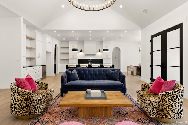 living area featuring light wood finished floors, visible vents, recessed lighting, arched walkways, and high vaulted ceiling