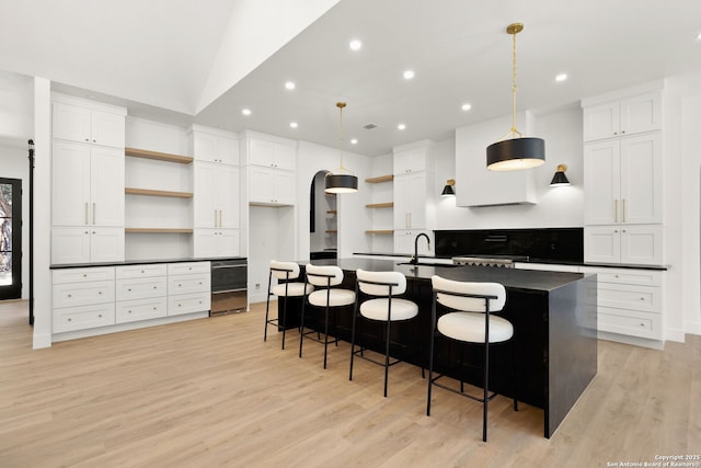 kitchen featuring dark countertops, a spacious island, light wood-style floors, and open shelves