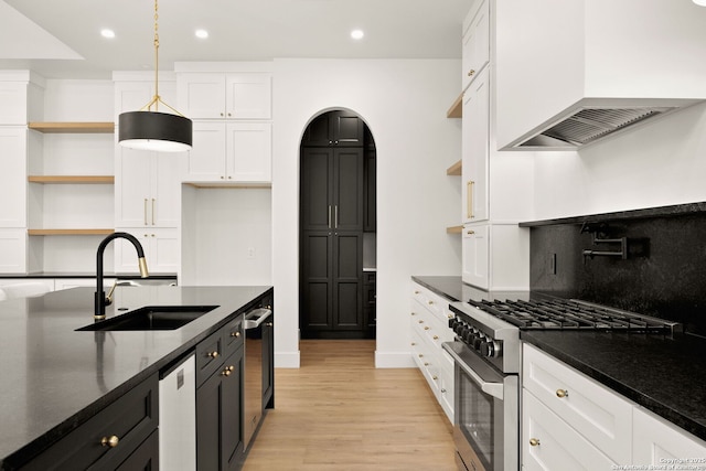 kitchen featuring high end stove, open shelves, premium range hood, white cabinets, and a sink