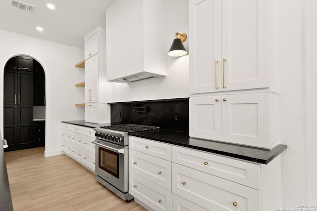 kitchen with dark countertops, visible vents, white cabinets, high end stainless steel range, and open shelves