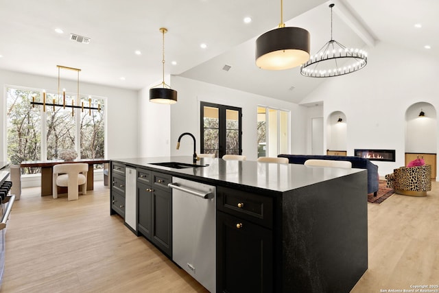 kitchen featuring a sink, stainless steel dishwasher, dark cabinetry, french doors, and light wood-style floors