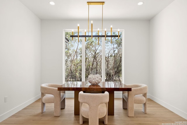 dining area with a chandelier, light wood finished floors, and baseboards