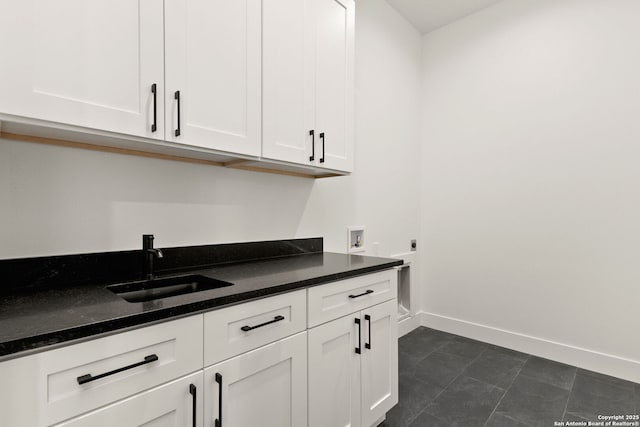 kitchen featuring white cabinets, baseboards, and a sink