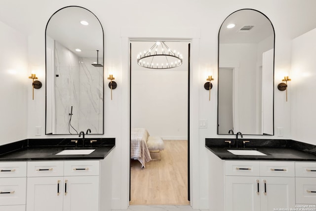 full bathroom with two vanities, visible vents, a marble finish shower, and a sink