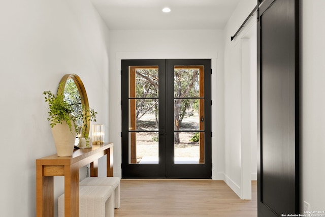 doorway featuring a wealth of natural light, french doors, a barn door, and light wood finished floors