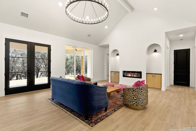 living area featuring beam ceiling, visible vents, light wood-style flooring, and french doors