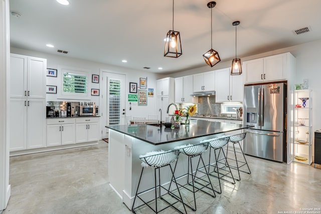 kitchen featuring dark countertops, visible vents, finished concrete flooring, decorative backsplash, and appliances with stainless steel finishes