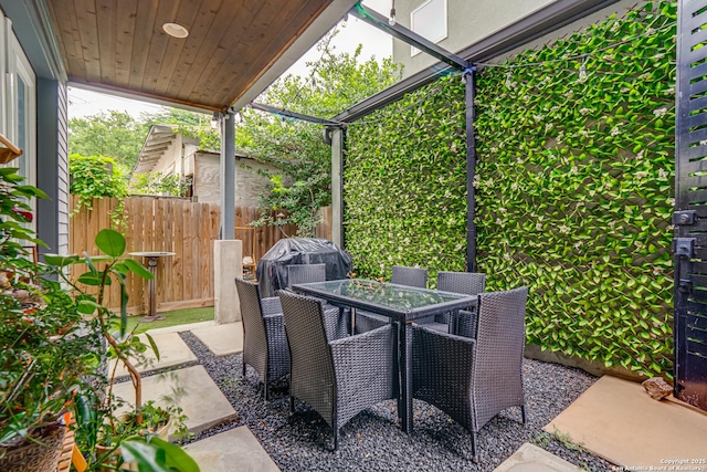 view of patio with outdoor dining area, fence, and a grill