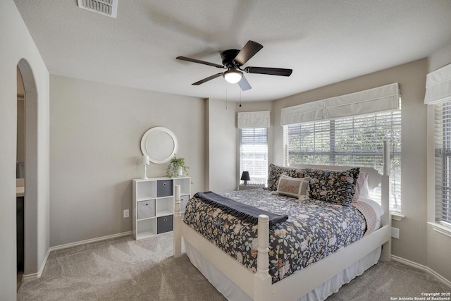 carpeted bedroom with visible vents, baseboards, a textured ceiling, and a ceiling fan