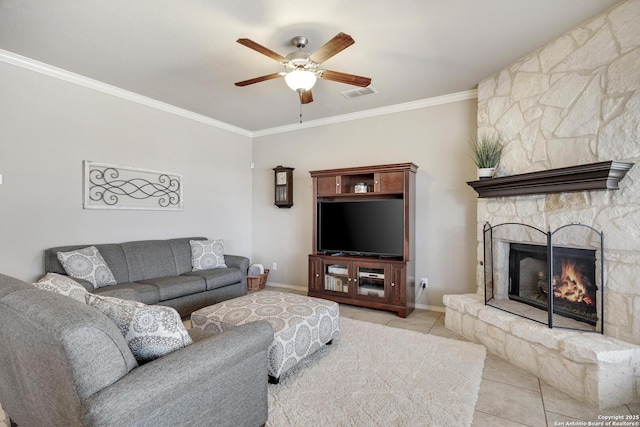 living room featuring tile patterned floors, visible vents, ornamental molding, a stone fireplace, and ceiling fan