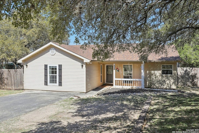 single story home featuring a porch, fence, and driveway